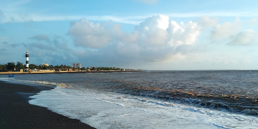 Daman beach with golden sand, gentle waves, and people enjoying the coastal view.