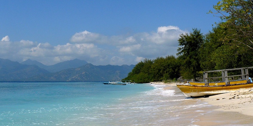 A famous spot for scuba diving in Gili island with a ferry parked and mountains visible afar