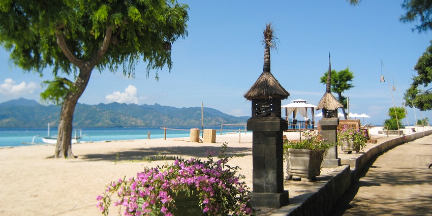 A picture of a beach in Indonesia having a distant island visible in the background