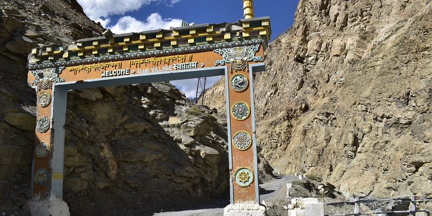 A picture of the entrance gate of Giu Mummy Village surrounded by rocky mountains.