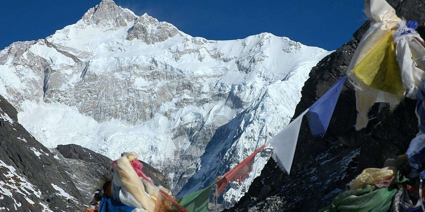 A breathtaking view of a snow-covered mountain range with prayer flags hanging in front.