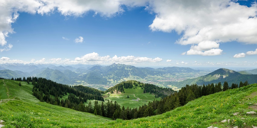 Green valleys stretch under a clear blue sky, showcasing nature's beauty and tranquillity.