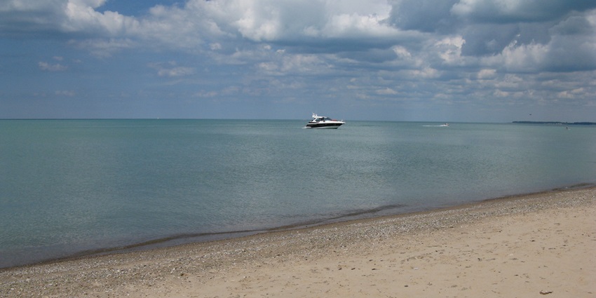 A panoramic view of the clear and calm blue waters of Grove Beach with mild waves