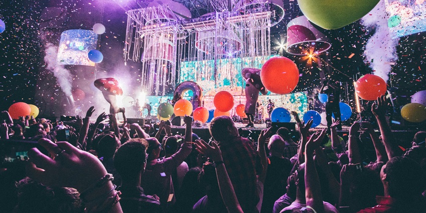 People standing and enjoying a performance in front of a stage at a live event.