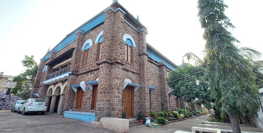 A picture of a church near the Bapu Museum with tall trees around the walking alley