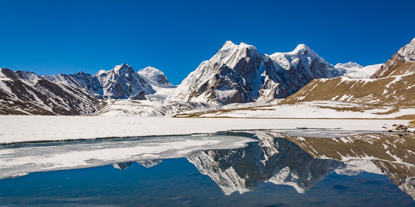 A picture of a high-altitude lake with a reflection of a nearby snow-capped mountain