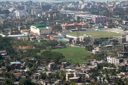 An aerial picture of a city with greenery, a cricket stadium, and housing apartments as seen during daytime