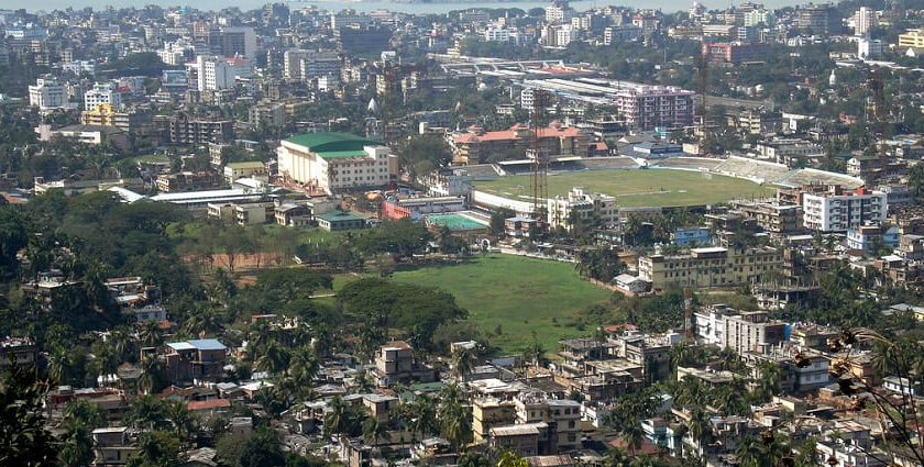 An aerial picture of a city with greenery, a cricket stadium, and housing apartments as seen during daytime