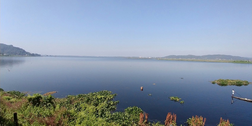 A breathtaking view of a pristine lake in Guwahati surrounded by lush green meadows.