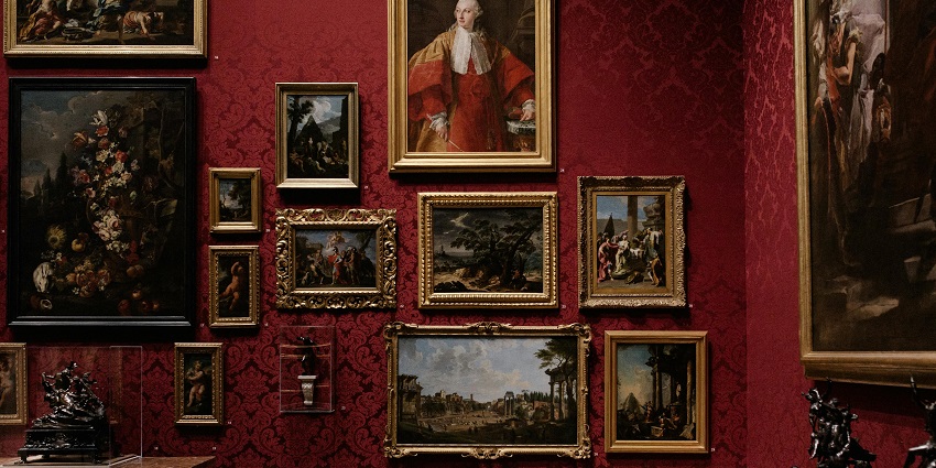 A picture of a red wall inside an art gallery in Guwahati with multiple paintings and art pieces at display for visitors