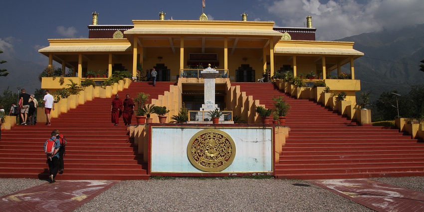 A picture of a staircase in front of a monastery with mountains visible in the background