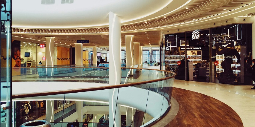 A view of a place to buy things with wooden flooring, glass railings, and a dustbin.