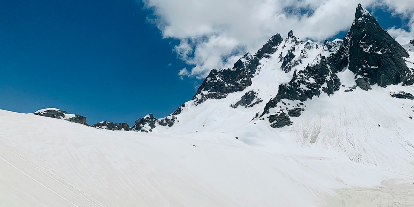 a picture of a snow-capped mountain taken while trekking in Kasol during daytime in cloudy weather