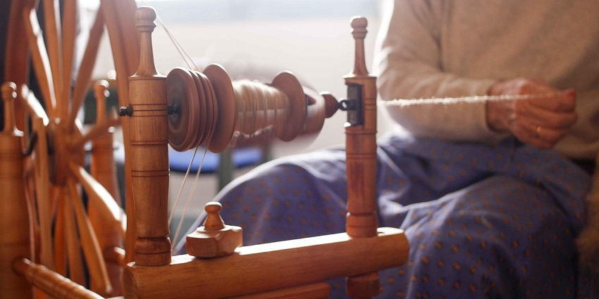 Image of a person loom weaving with traditional items - explore handloom market of Bongaigaon