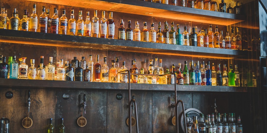 A picture of a cabinet in a Bar with multiple bottles at display under well-lit conditions