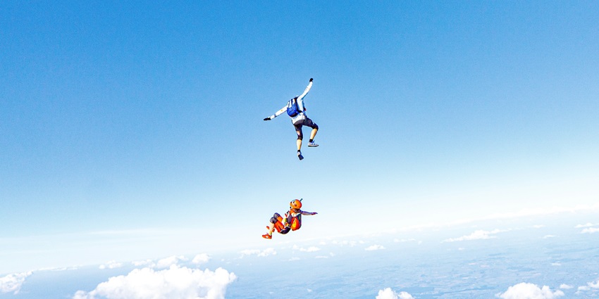 Two people soaring through the air on parachutes, enjoying a skydiving Vietnam experience.