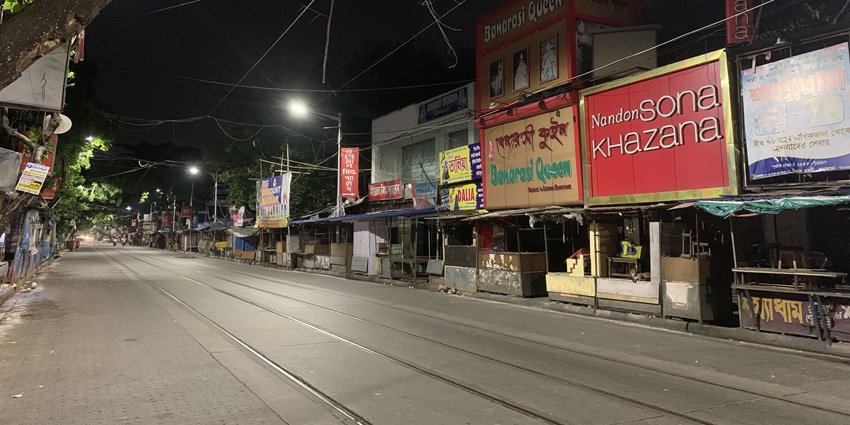 A picture of an empty street with closed shops on both sides, taken during nighttime