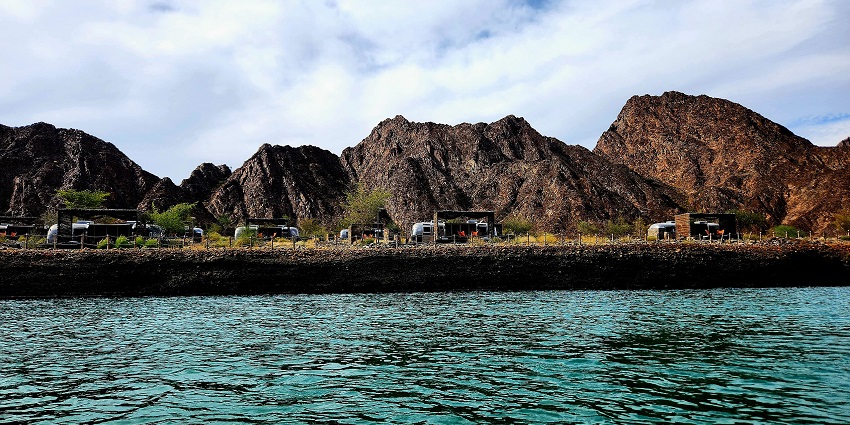 A scenic view of a dam in Hatta with a lake in front and mountains in the background