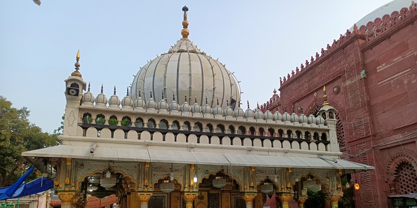 Hazrat Nizamuddin Auliya Shrine with white dome, arched entrance, and prayer visitors