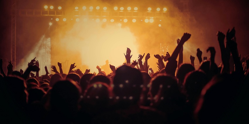 Crowd enjoying a concert with bright stage lights and live music.