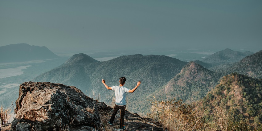 A panoramic view of a man standing on a hilltop at the famous Nakkati Hill in Assam.