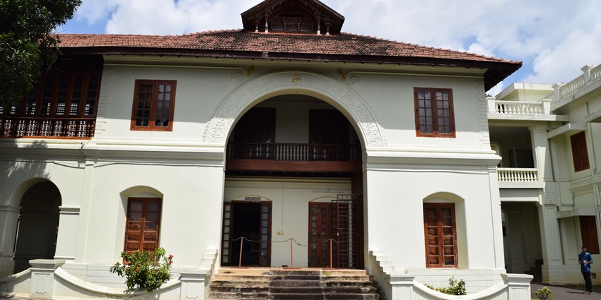The frontal view of an old, white building in Kerala that's turned into a museum
