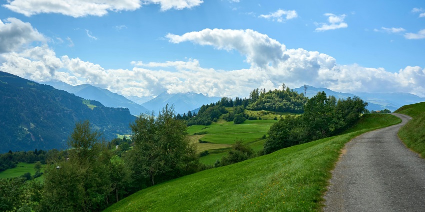 Road winding through a landscape with a view of hills and mountains in the distance.