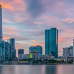 A scenic view of towering buildings surrounded by glistening waters of the region.