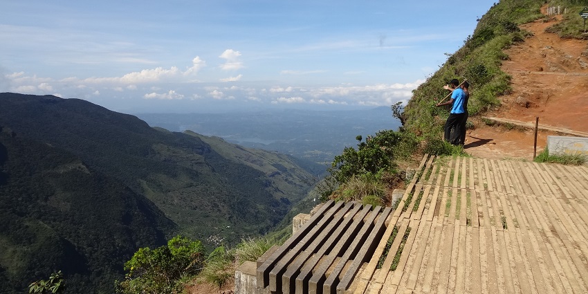 Scenic view of Horton Plains National Park with lush greenery, misty mountains.