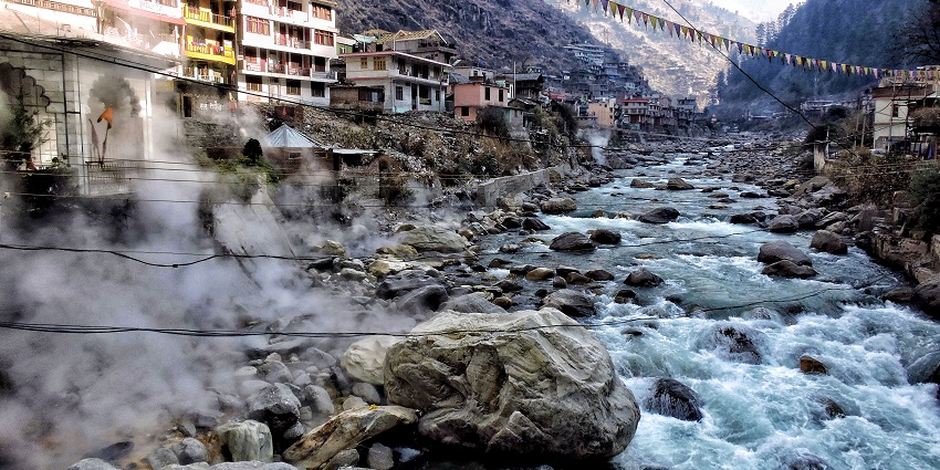 A stunning view of hot springs in Manikaran with houses and temples on the side.