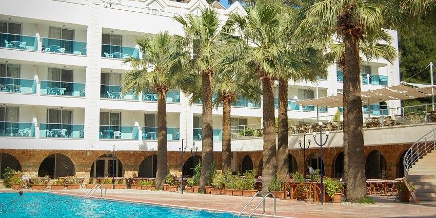 Image of the beautiful white block hotel building with palm trees and a clean pool