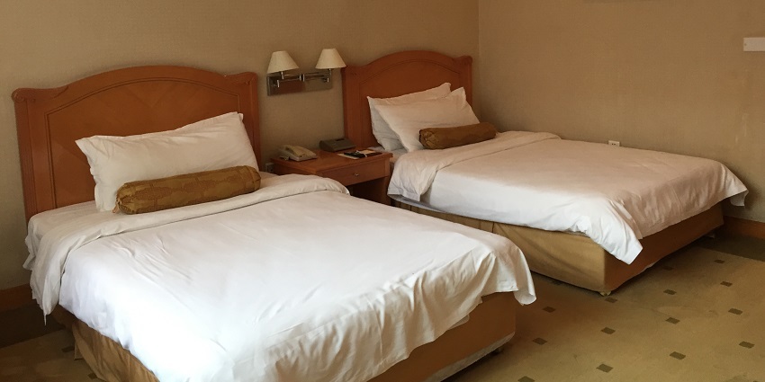 Snapshot of a hotel room cleansed having a bed with whte sheet and pillow