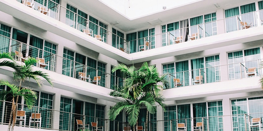 View of the balconies of a hotel with chairs for sitting and green curtains on windows.