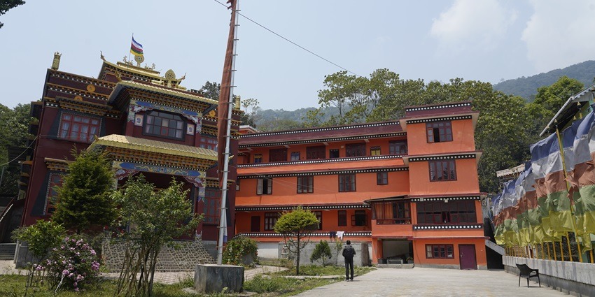 A monastery surrounded by trees and with mountains in the background