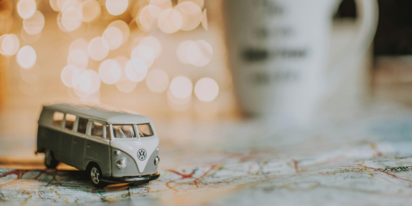 A selectively focused view of a miniature grey van on a colourful map during the daytime.