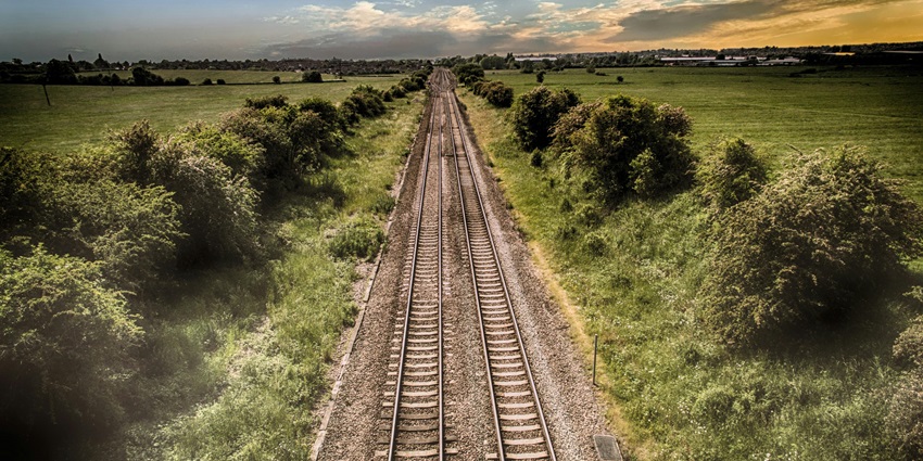 A mesmerising view of railway track surrounded by lush greenery during the daytime.