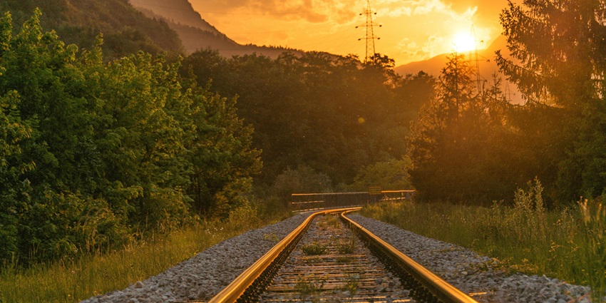 A breathtaking view of a railway track surrounded by trees during the evening time.