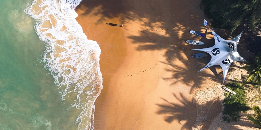 Rhythmic waves hitting the sprawling sandy shores of Hua Hin Island decked with trees.