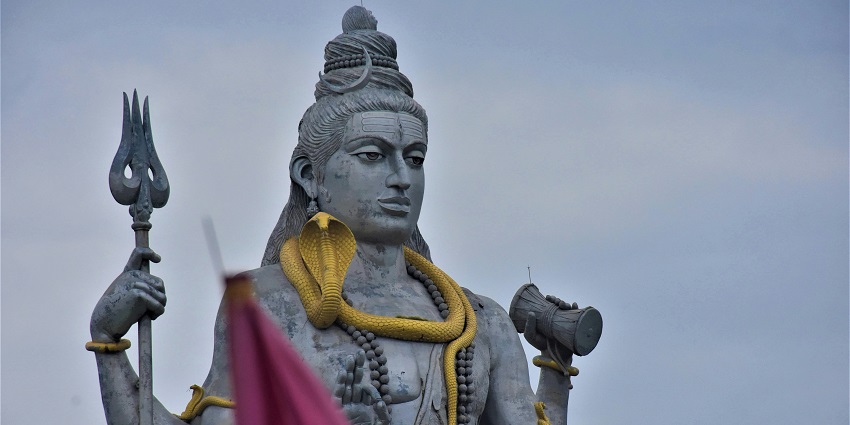 Majestic statue of Lord Shiva, surrounded by lush greenery and a serene atmosphere.