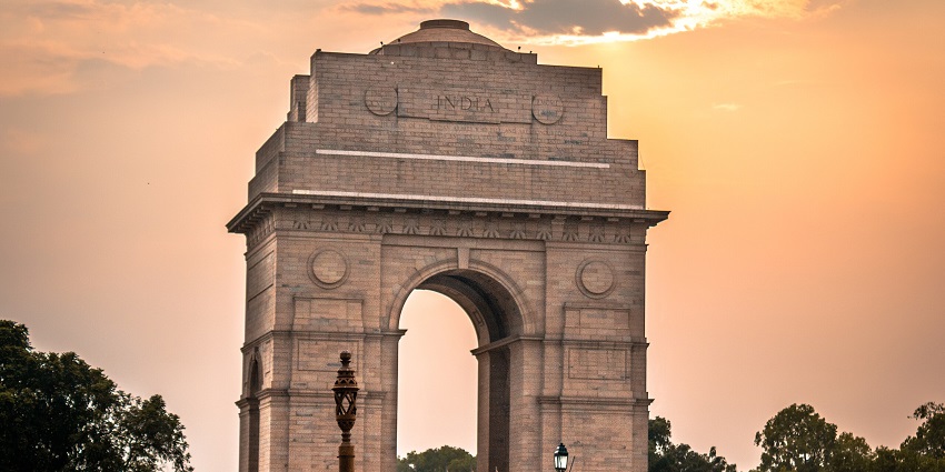 India Gate at sunset in New Delhi with warm sky colours and silhouetted monument.