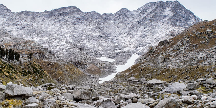 A picture of a trekking trail with a hint of snow and mesmerising views of the Himalayas