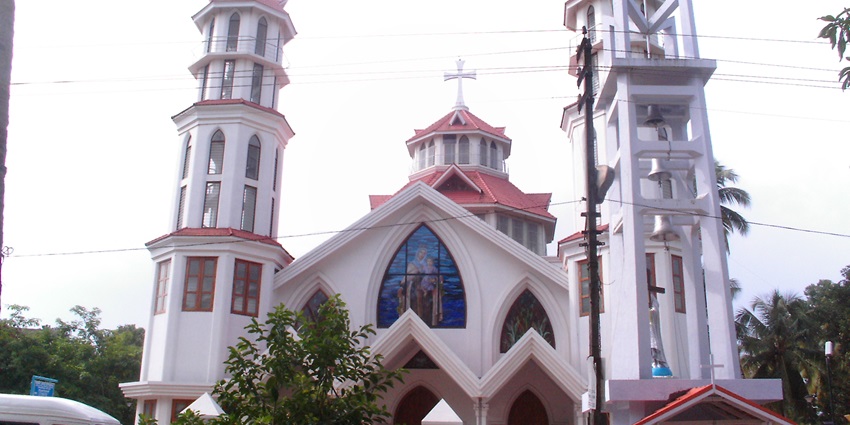 A frontal view of a church in Kollam with white walls and a huge cross over its roof
