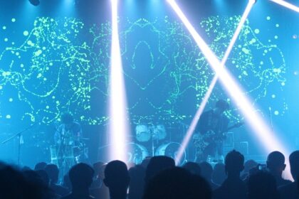 A fascinating view of a party in a club with blue lights and people performing in front.