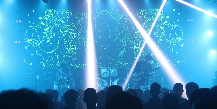 A fascinating view of a party in a club with blue lights and people performing in front.