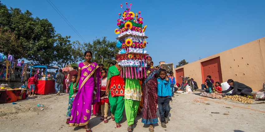 A picture of a festival celebration in West Bengal with people carrying a decorated garland
