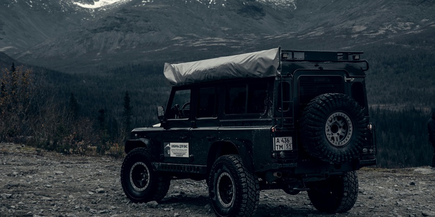 A stunning view of a black jeep with mountains in the background during the daytime.