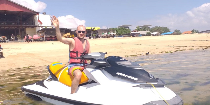 A man sitting on a jet ski at a beach in Bali, enjoying the water sports