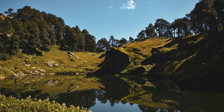 An idyllic view of Jibhi featuring tranquil crystal-clear waters and lush green vegetation.