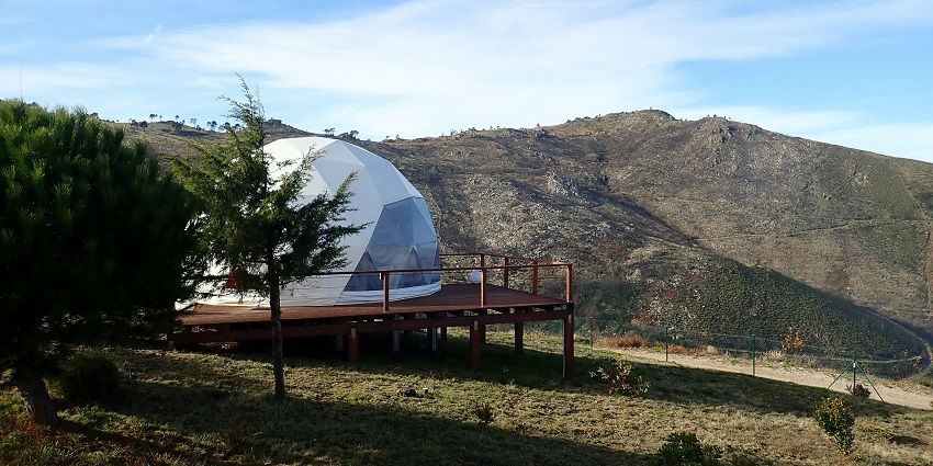A glimpse of a spherical stay surrounded by majestic mountains and lush greenery.