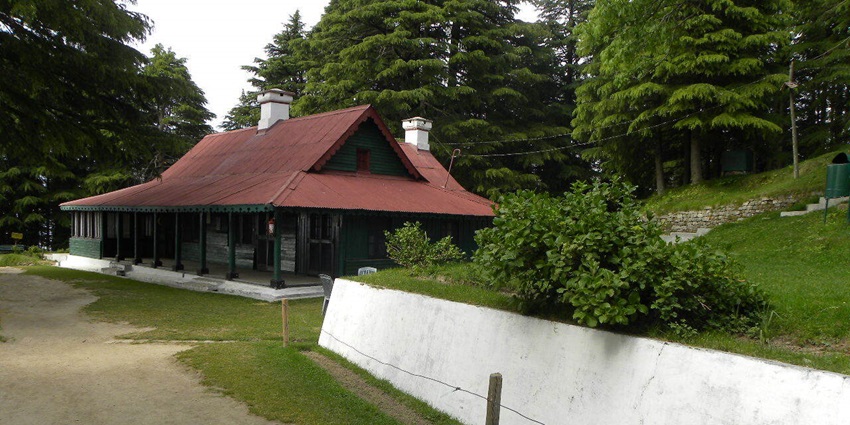 Scenic entrance to Kalatop Wildlife Sanctuary, surrounded by lush greenery and tall trees.